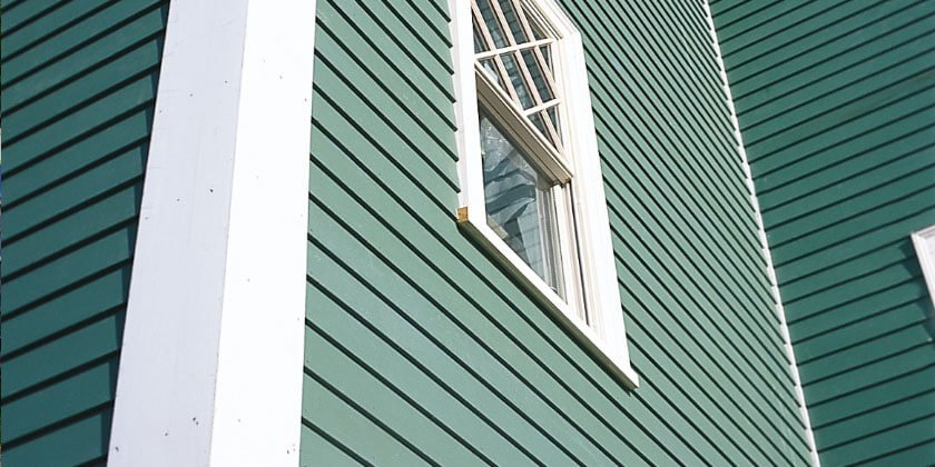 A partially open window on a green horizontal clapboard siding installed by a general contractor in Malden, CA.